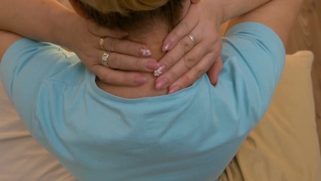 Top view of middle aged woman rubbing back of neck healing the pain and stiffness