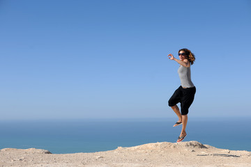 eine hippie Frau springt vor weitem Himmel und Meer