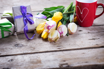 Yellow and white spring tulips, wrapped  boxes with presents  and red cup with heart