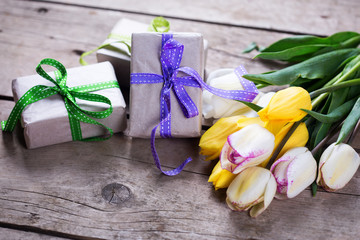 Yellow and white spring tulips and wrapped  boxes with presents