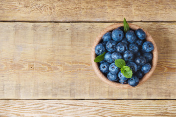 Delicious blueberries, green mint leaves wooden bowl on canvas jute cloth vintage rustic table. Bilberry on horizontal  background. Healthy eating antioxidant nutrition concept. Top view, copy space.