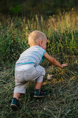A boy is walking along a clearing in the grass