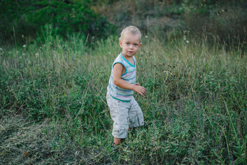 A boy is walking along a clearing in the grass