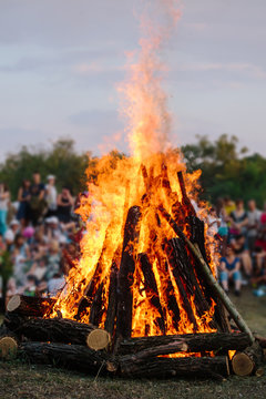 Unrecognizable people watch as huge bonfire burns