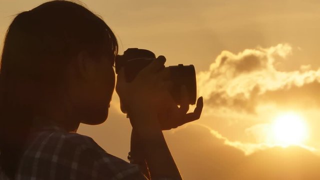 Silhouette of Vietnamese girl photographer taking pictures against the background of evening clouds