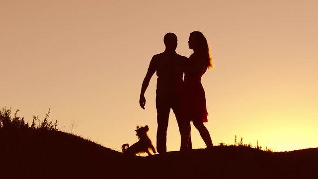 Couple in love dancing silhouette at nature sunset and kissing. Loving man and woman with dog dancing silhouette slow motion video