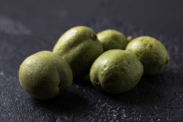 Fresh green walnuts in the skin just from the tree. Walnuts on a black background. Macro.