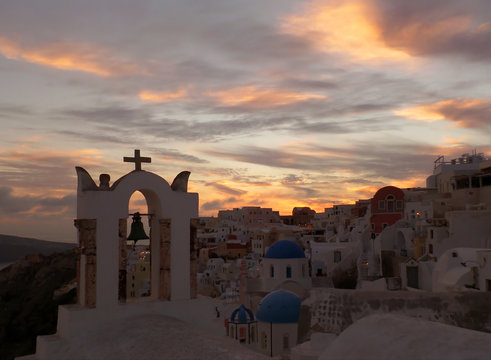 Church bell-tower against pastel color of evening sky at Oia village, Santorini Island, Greece 