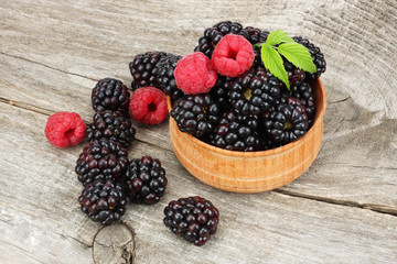 blackberries with raspberries in wooden bowl on old wooden table background
