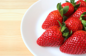 Vibrant Red Fresh Ripe Strawberries Lined up on a White Plate on Wooden Table 