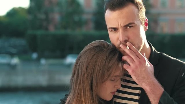 Smoking man hugging a young woman. Romantic hugging lovers