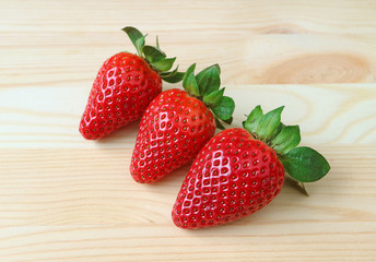 Three Vibrant Red Color Fresh Ripe Strawberry Fruits Isolated on Wooden Table 