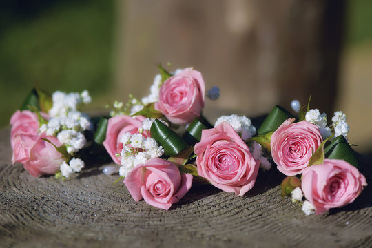 Flower arrangement for wedding centerpiece featuring small pink roses and baby's-breath, positioned on a tree stump, with shallow depth of field
