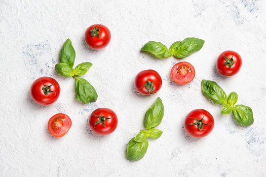 Fresh cherry tomatoes with basil leaves on a stone table, vegetable pattern, top view