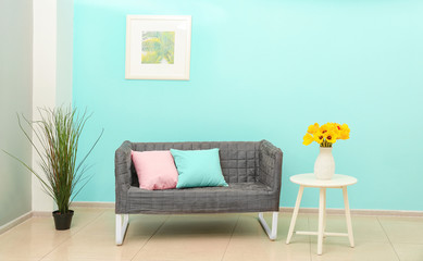 Interior of light modern room with dark sofa, table and floral decor