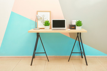 Workplace with computer in room near color wall