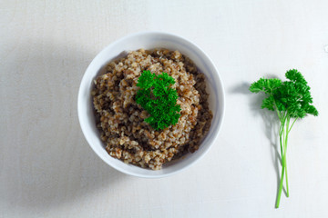 Buckwheat porridge with parsley on a white wooden background. Top view.