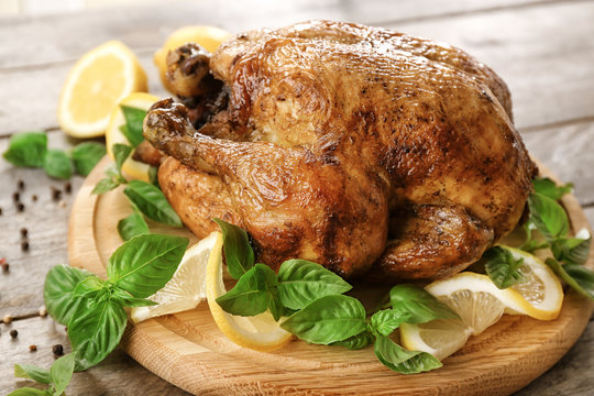 Tasty whole roasted turkey with lemon and basil on wooden board