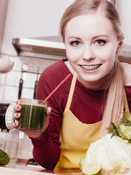 Woman in kitchen holding vegetable juice