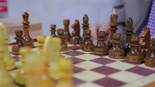 Closeup of person playing chess game on a wooden board in the gameroom