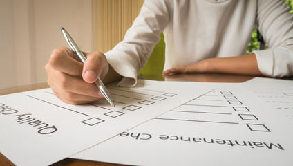 Close- up hand holding pen on quality check paper and the format for filling in information in business concept,vintage style and softtone.