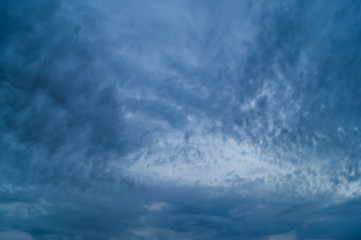 Obraz premium Grey dark fkuffy clouds on the blue sky at sunset or sunrise. Stormy weather.
