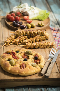 gegrillte Fleischspiesse, mediterranes Ofenbrot mit Oliven und getrockneten Tomaten, Schafskäse mit Rosmarin und Salatblättern garniert, Studio