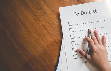 Close- up hand with pen on to do list paper and the format for filling in information in business concept,vintage style and soft tone.