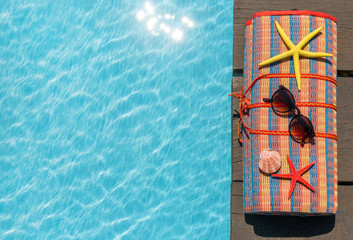 Beach Mat and sunglasses on the edge of the pool with its turquoise and clear waters