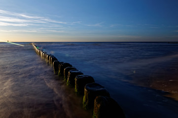 Poland, Baltic. Sunset over the sea. Breakwater on the smooth surface of the sea.