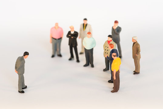 Mobbing / Diskriminierung - Gruppe schaut auf Außenseiter - Szene mit Miniaturfiguren