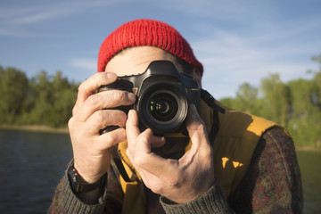 Obraz premium Closeup Portrait of a Man Taking a Picture with Professional Photo Camera on a Lake.