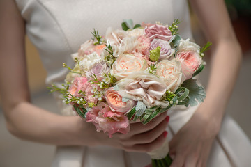 Horizontal shot of bride holding pastel colors roses and silk accent wedding bouquet
