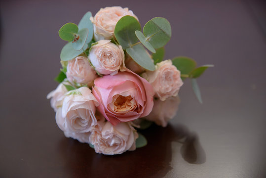 Horizontal shot of glamorous wedding bouquet featuring pink peonies and greenery  positioned on a mauve glossy background