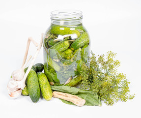 Brined pickles in a jar, with all the ingredients for making them (garlic, dill and horseradish)