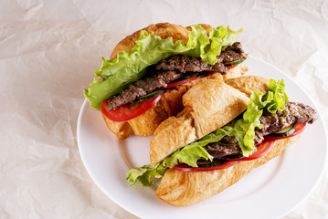Two croissants with meat on a plate