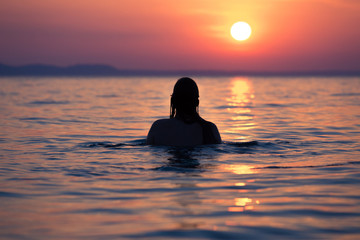 Fototapeta premium Female in ocean at sunset