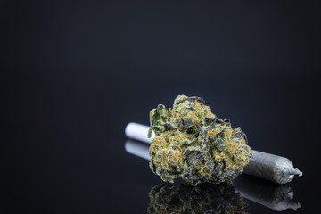 Close Up Macro Of Marijuana Bud With Joint On Dark Black Table Background. Selective Focus With Copy Space.