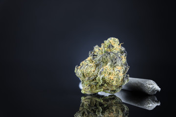 Close Up Macro Of Marijuana Bud With Joint On Dark Black Table Background. Selective Focus With Copy Space.