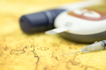 Close up of syringe for insulin and Glucose meter for check blood sugar level on world map using as World medicine, diabetes, glycemia, health care and people concept