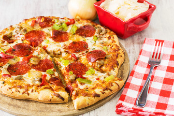 Pepperoni Pizza With Slice Taken Out and Fork on Napkin