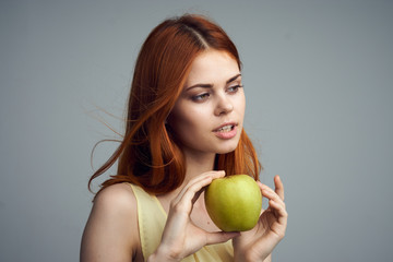 Beautiful young woman on a gray background holding an apple