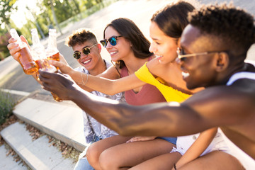 Group of young people toasting with beer in an urban area.