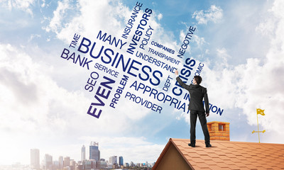 Young businessman standing on house roof and writing leadership skill concept. Mixed media