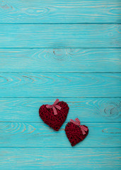 Valentine's Day. Decorative wicker hearts of burgundy color on azure wood background.
