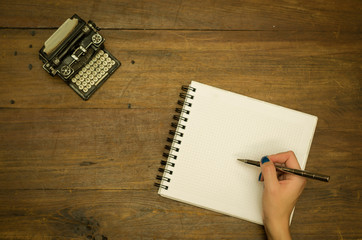 Mão de mulher escrevendo em caderno em branco com caneta, bebendo café, objetos de decoração