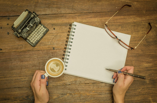 Mão de mulher escrevendo em caderno em branco com caneta, bebendo café, objetos de decoração