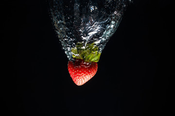 A strawberry splashing into water