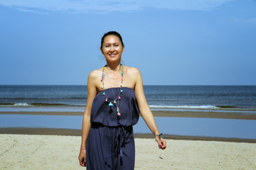 Fototapeta premium Baltic sea, woman with dark hair walking on beach in dress