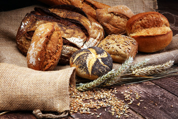 Different kinds of bread and bread rolls on wooden table